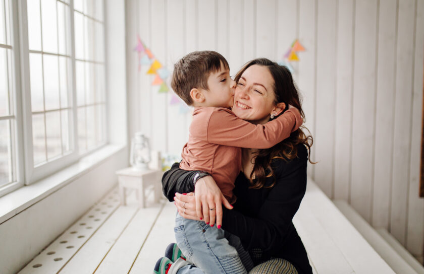 Mother and her son are posing in the studio and wearing casual clothes